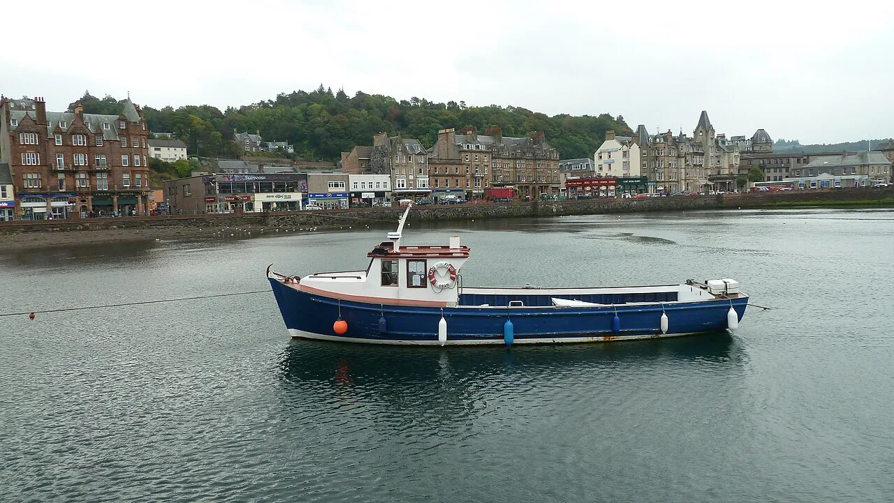 A boat in Oban Bay with the town behind.