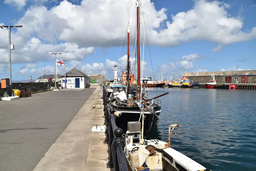 A sailing boat moored at the pier in Kirkwall Harbour.
