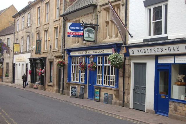 The Heart of All England public house on a high street of stone-built shops.