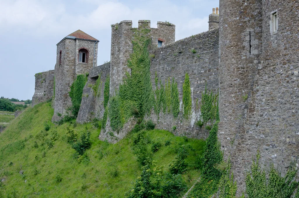 The curtain walls of Dover Castle on a grassy bank.