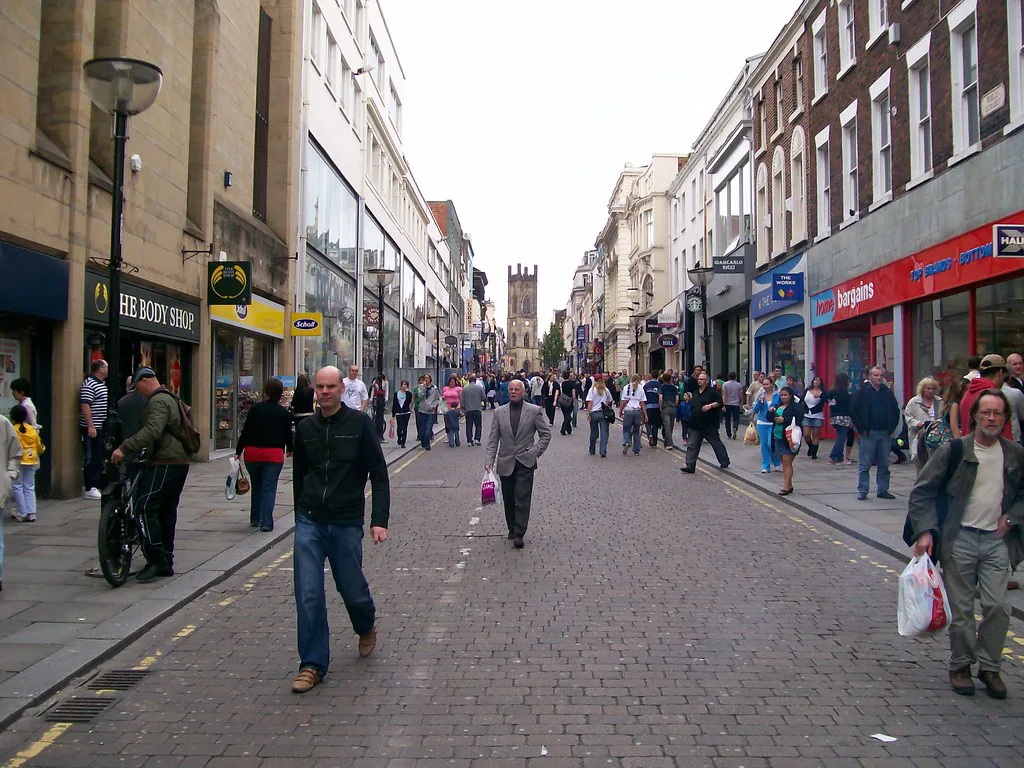 Shoppers on Bold Street, Liverpool, with a church tower at the top of the street.