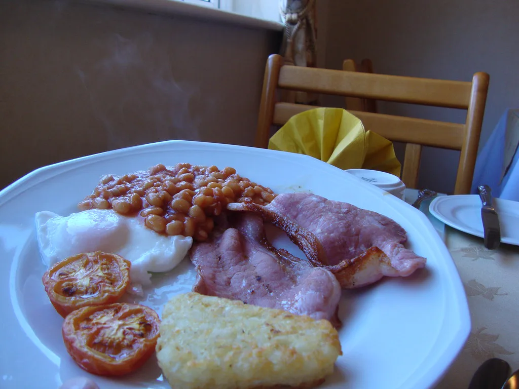 A full English breakfast with eggs, bacon, beans, tomatoes and hash brown.
