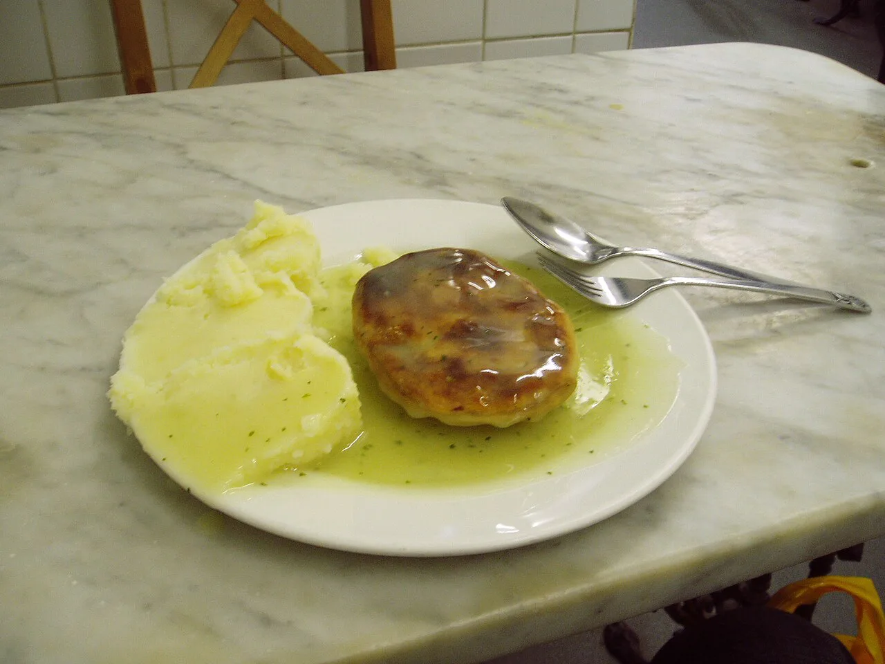 A traditional pie and mash meal with liquor on a marble table.